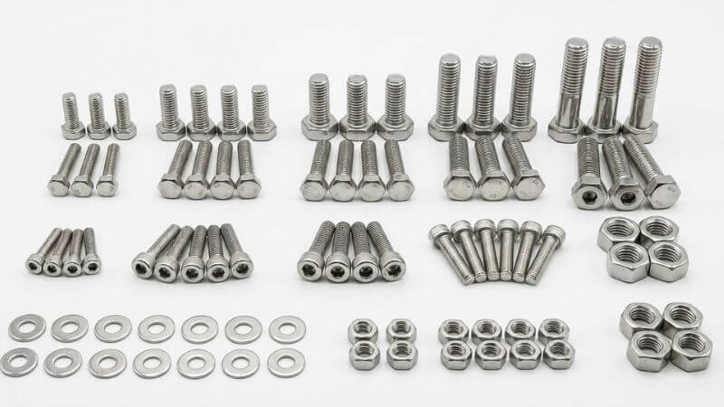 Colección de tornillería en acero inoxidable mostrando tornillos, tuercas y arandelas de diferentes tamaños y tipos